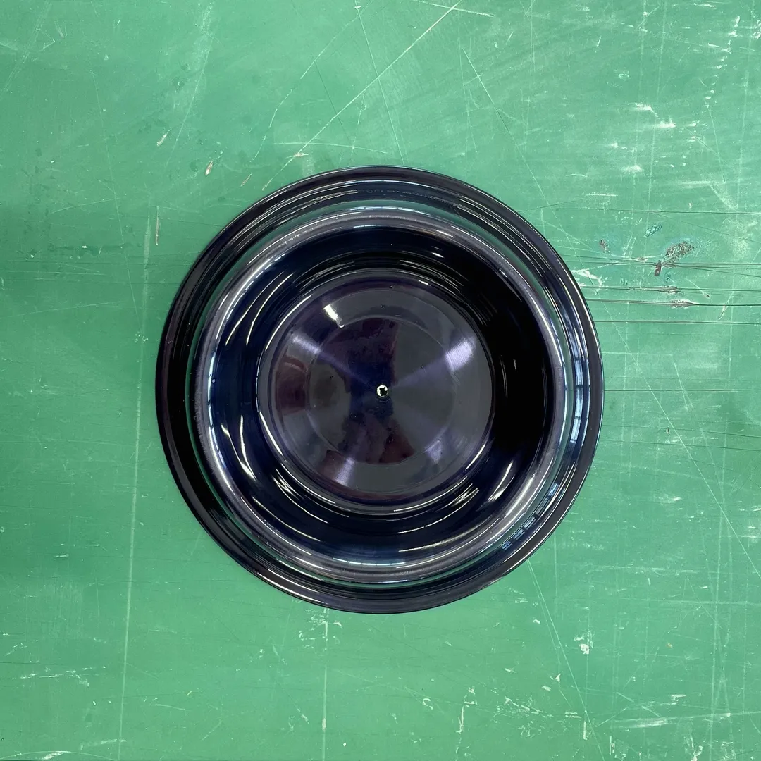 Top down view of a black dog bowl on a green table top.