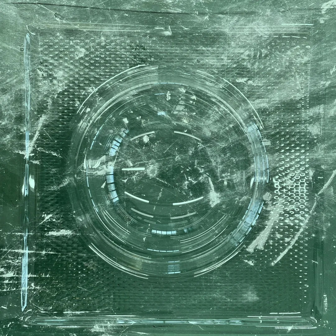 Top down view of a transparent dog bowl on a green table top.